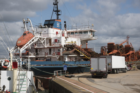 Ship alongside a quay with ship supplies delivery lorries