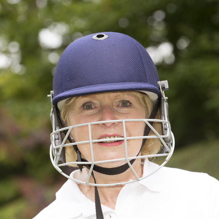 Portrait of an elderly woman cricketer wearing a batswomans' saftey helmetの写真素材