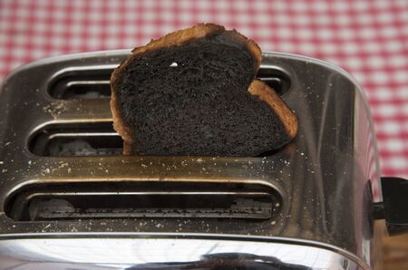 Slice of burnt toast in a toaster machineの写真素材