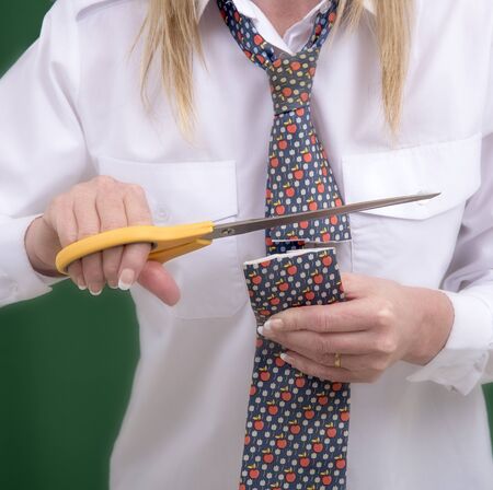 Woman using scissors to cut a necktie in half for a jokeの写真素材