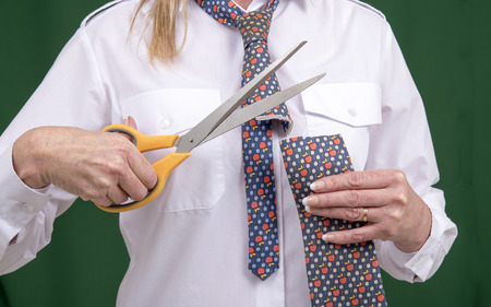 Woman using scissors to cut a necktie in half for a jokeの写真素材