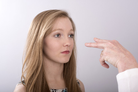 A two fingure gesture towards a young woman's eyesの写真素材