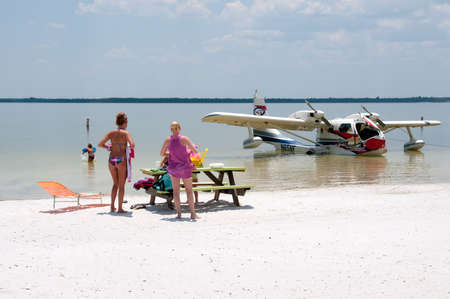 Holidaymakers on the beach and a seaplane on Lake Weir Florida USA