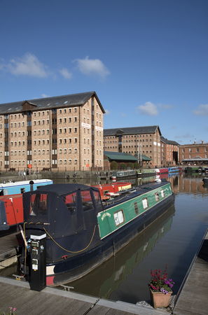 Gloucester Docks Gloucestershire England UK - October 2016 - Narrowboats berthed with a backdrop of refurbish warehouse in the docks which date from 1827のeditorial素材