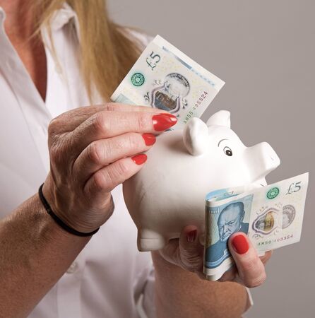 Woman holding a piggy bank and new five pound notes