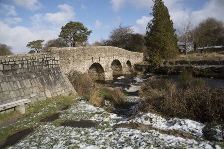 The East Dart River flows below a stone road bridge built in the 1700's at Postbridge on Dartmoor in Devon England UKの写真素材