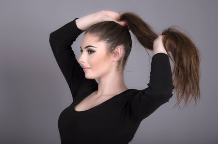 Portrait of a teenage girl holding her long dark coloured hairの写真素材