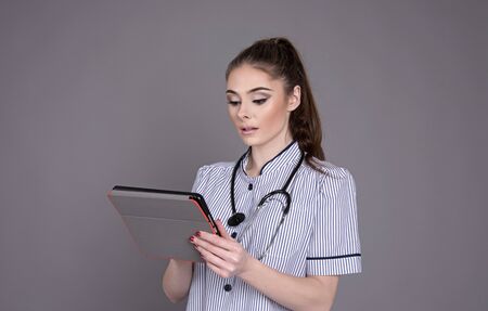 Nurse in uniform with a stethoscope and electronic tabletの写真素材
