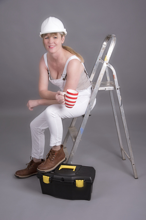 Worker wearing dungarees taking a tea break at her place of workの写真素材