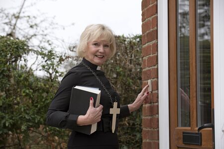 Elderly woman vicar making a house call in her parish in the English countryside