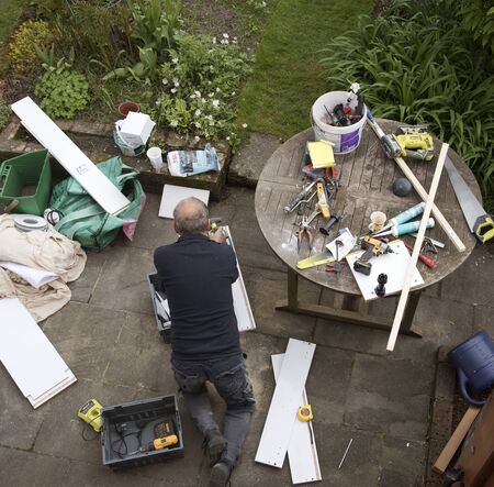 An overview of a handyman engaged in some DIY work on the garden patioのeditorial素材