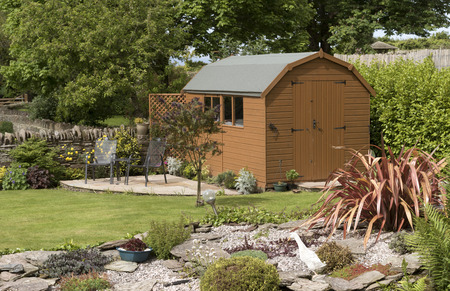 A Dutch barn style garden shed with a patio in a English country gardenのeditorial素材