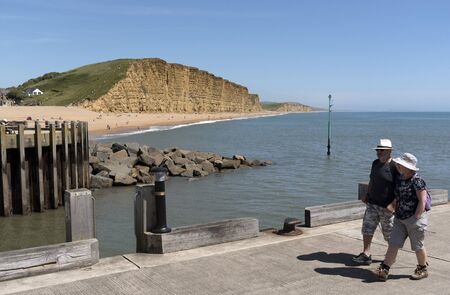 The Jurassic coastline viewed from the harbour entrance at West Bay in West Dorset England UK. June 2017. The golden strata of the East cliff.のeditorial素材