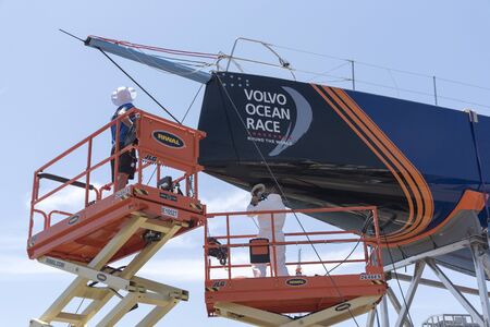 Cape Town waterfront South Africa. December 2017. Volvo Ocean Race. Racing yacht Vestas. Polishing the hull by team members using scissor liftsのeditorial素材