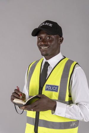 Police officer wearing a cap and reflective uniform jacket taking notes.の写真素材