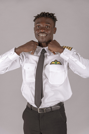 A young airline pilot with an african dred hairstyle. Crew member tying his black tie,の写真素材