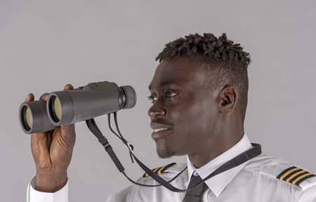 Young airline pilot using a pair of binoculars.