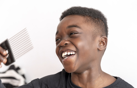 Nine year old boy with curly hair holding a wide tooth afro comb for his hair.の写真素材
