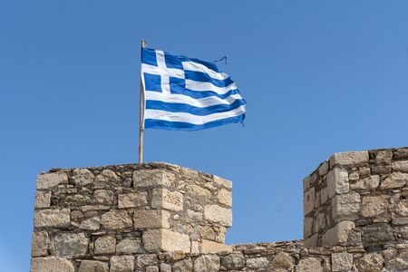 Ierapetra, Crete, Greece, June 2019. The Greek flag flying from the fortress wall in Ierapetra, Crete.の写真素材