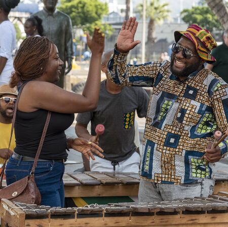 Cape Town, South Africa. Dec 2019. Zylophone player playing in a band busking on the waterfront high five's with an audience member. Cape Town.のeditorial素材
