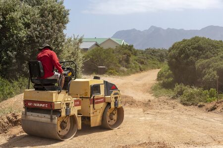 Rooiels, Western Cape, South Africa. December 2019. Worker rolling earth to prepare the ground to lay a brick road in the small hamlet of Rooiels.のeditorial素材