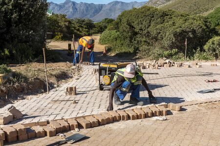 Rooiels, Western Cape, South Africa. December 2019. Workers laying a brick road in the small hamlet of Rooiels.のeditorial素材