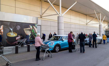 Southampton, England, UK, March 2020. Social Distancing people waiting in line at a supermarket in...