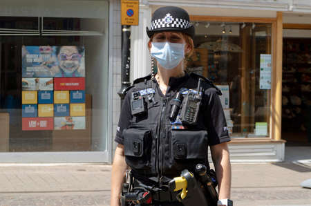 Newbury, Berkshire, England, UK. June 2020. A policewoman wearing a mask patrols the High Street in Newbury, Berkshire during the Covid-19 epidemic.のeditorial素材