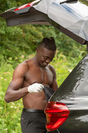 England, UK. 2020.  Car driver with the boot open seen changing his clothes
