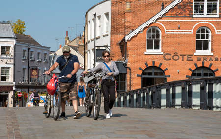 Eton, Buckinghamshire, England, UK. 2020. Cyclists push their bicycles over the Windsor Eton bridge...