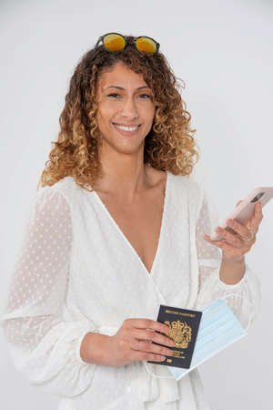 England, UK, 2021. Attractive woman holding a new UK passport, a  mask and using a mobile phone.の写真素材