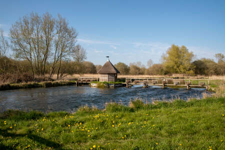 Longstock, Hampshire, England, UK. The River Test as it flows through Longstock with a thatched...