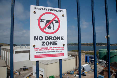 Cornwall, England, UK. 2021.  No Drone Zone sign on railings outside an industrial area.