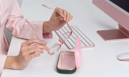 Salisbury, England, UK. 2021.  Womans hands removing glasses from case with back drop of computer and keyboard.の写真素材