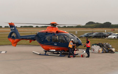 Cornwall, England, UK.2022. Airlift helicopter ground crew attaching carry strap to underbelly of aircraft and then to the cargo in a net.のeditorial素材