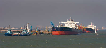 Fawley, Southampton, England, UK. 2022.  Three ocean going tugs alongside a jetty and oil tankers discharging their cargo of oil at Fawley refinery on Southampton Water, UK.の写真素材
