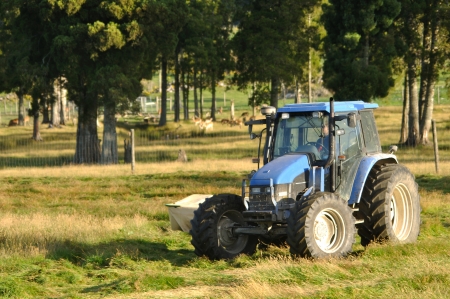 Tractor mowing pasture for silage, West Coast, South Island, New Zealandの写真素材