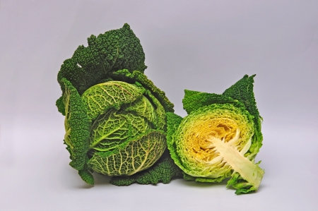 whole and sliced crinkly cabbage on a seamless background