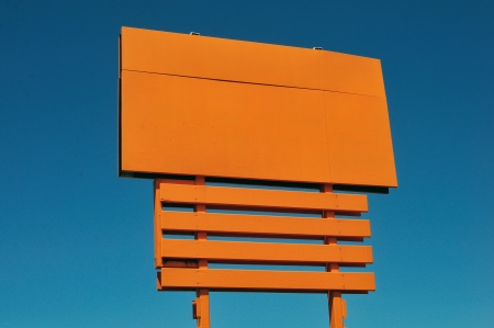 blank orange billboard against blue skyの写真素材