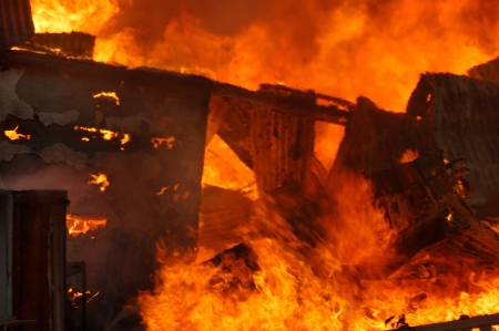 flames and smoke rise from burning buildingの写真素材