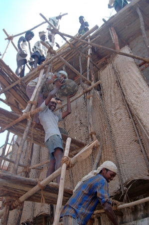 TAMIL NADU, INDIA, circa 2009: Unidentified men pass up bowls of cement at a construction site, circa 2009 in Tamil Nadu, India. Much of India's economy still relies on hand tools and skilled tradesmen.のeditorial素材