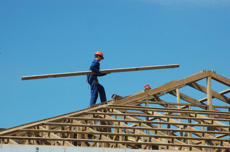 builder carrying timber for the roof framingの写真素材