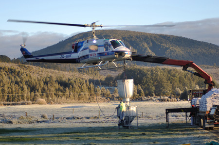 GREYMOUTH, NEW ZEALAND, CIRCA 2009: Workers fill monsoon bucket on Iroquois helicopter with 1080 pellets to kill possums near Greymouth, New Zealand. The 1080 pellets are a controversial method of controlling possums in New Zealand's native bush.のeditorial素材