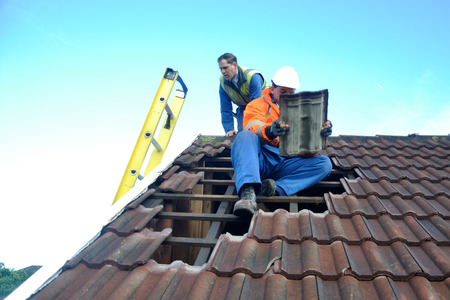 GREYMOUTH, NEW ZEALAND, APRIL 17, 2014: Volunteer workers replace tiles on a house damaged in Cobden...