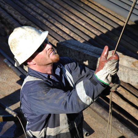 GREYMOUTH, NEW ZEALAND, 21-4-2009: Drilling crewman directs cable being lowered into an oilwell.