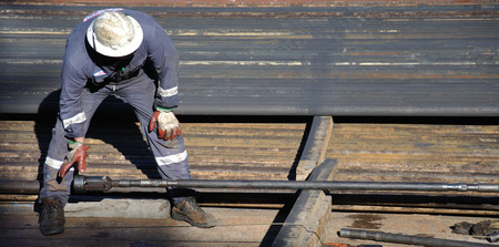 GREYMOUTH, NEW ZEALAND,  CIRCA 2006: Unidentified worker attaches a tool to the tip of the drillstring at an oil well drilling rigのeditorial素材