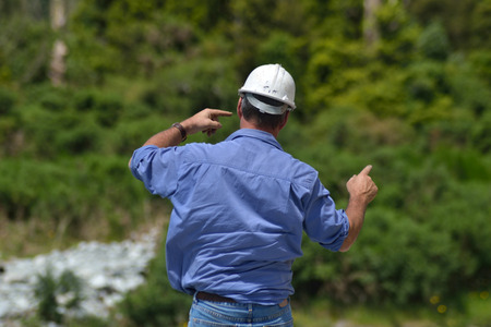 Building foreman instructs his crane driver while constructing a concrete bridge over a small river...