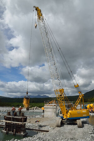 GREYMOUTH, NEW ZEALAND, DECEMBER 2013: Builders construct a concrete bridge over a small river in...