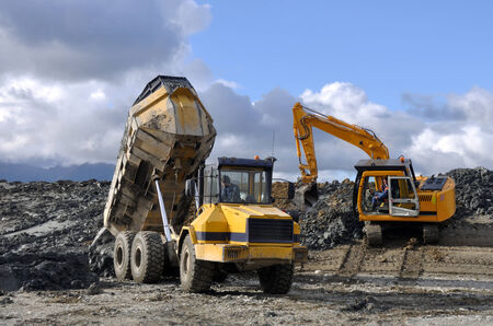 A 10 ton digger shifts clay for lining a dairy effluent pond while a dumpster delivers more clay,...
