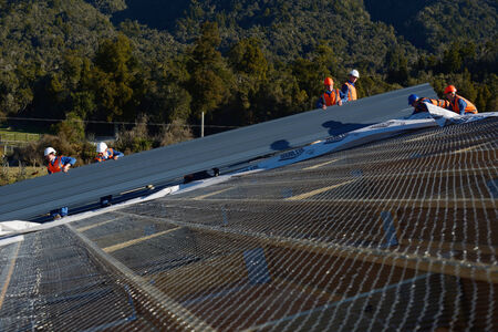 GREYMOUTH, NEW ZEALAND, SEPTEMBER 6, 2014: A team of contractors put the roof on a large commercial building near Greymouth, New Zealand, September 6, 2014のeditorial素材